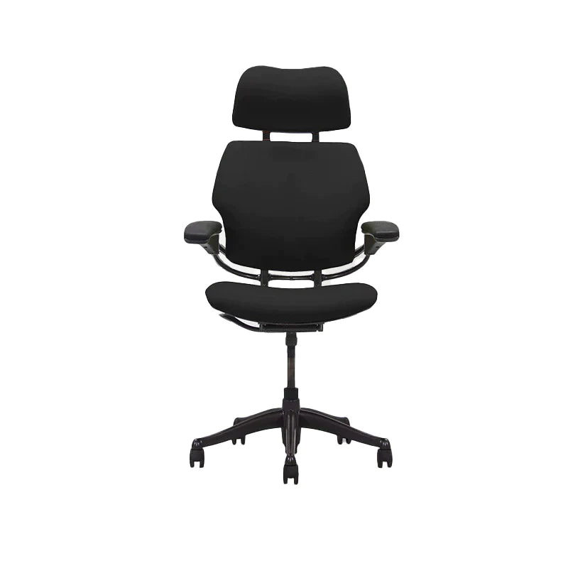 A Humanscale Freedom office chair with a headrest, featured in black. The chair has a high back design with contoured cushions, adjustable arms, and a headrest for ergonomic support. It is set on a five-star base with casters for mobility. The chair's sleek, modern profile is designed for comfort and style in any office environment.